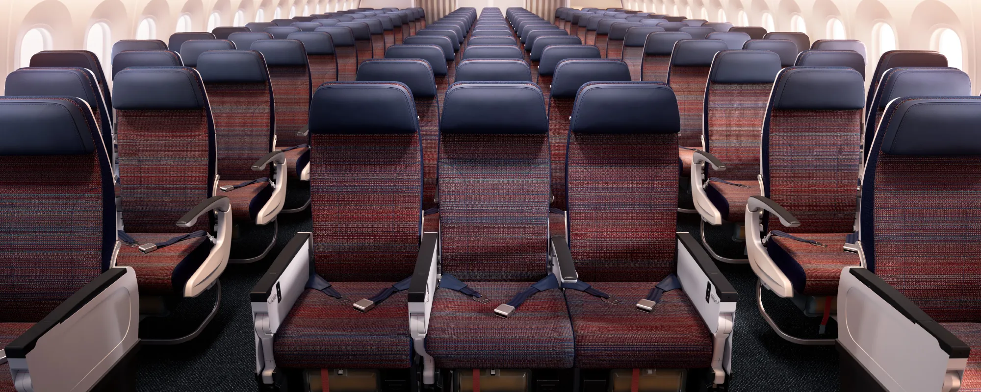 Ekonomická třída letadla Korean Air Boeing 787-10 s textilními sedadly v modro-červeném designu, uspořádaná v řadách po třech, pohled do celé kabiny.